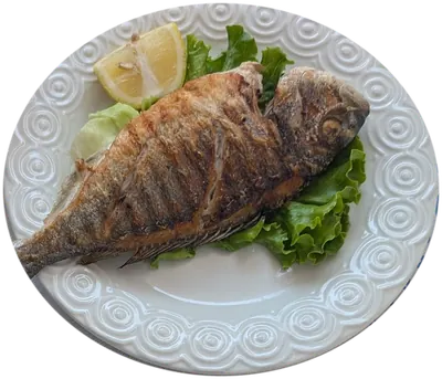 Grilled sea bream with lemon and lettuce on a white plate