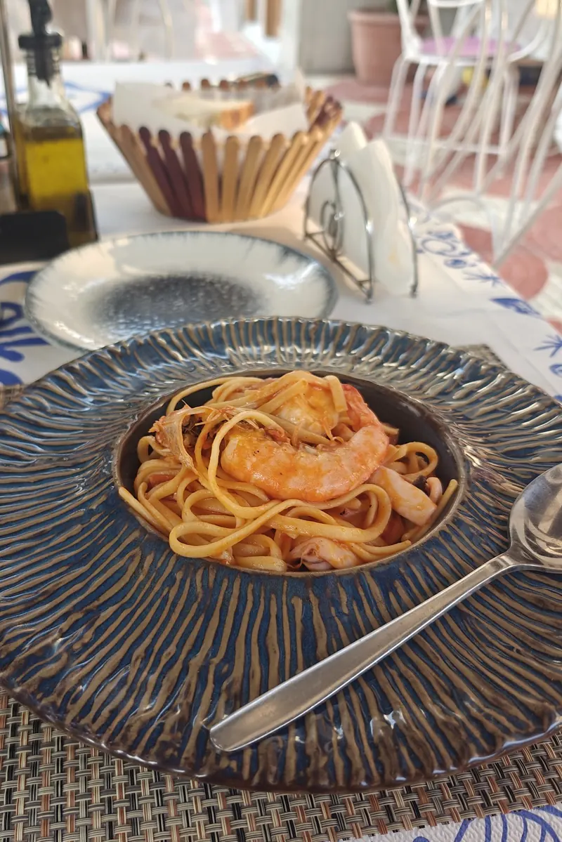 Linguine with prawns in a dark ceramic bowl