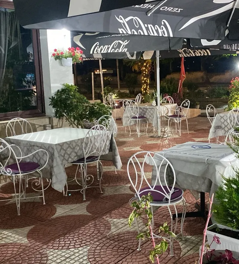 Evening on the terrace, lit cypresses and tables set for dinner
